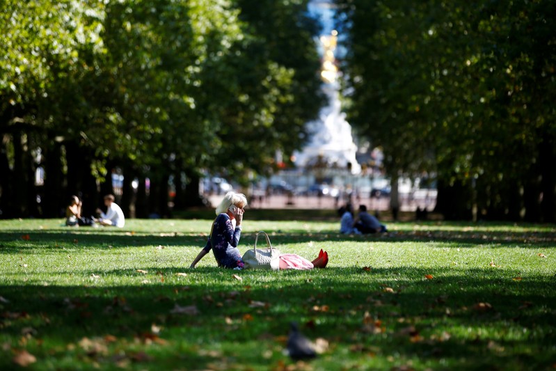 FILE PHOTO: A woman talks on her mobile phone whilst sitting in a park in central London