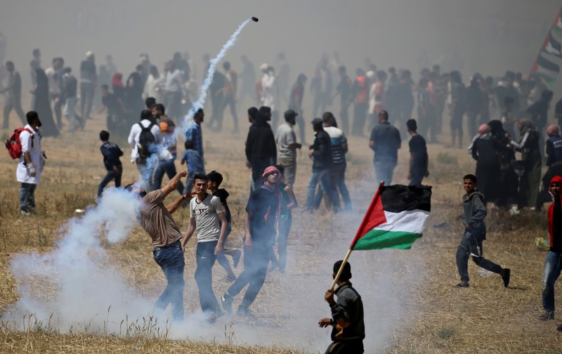 Palestinian demonstrator hurls back a tear gas canister fired by Israeli forces during protest marking the 71st anniversary of 'Nakba' at the Israel-Gaza border fence in the southern Gaza Strip