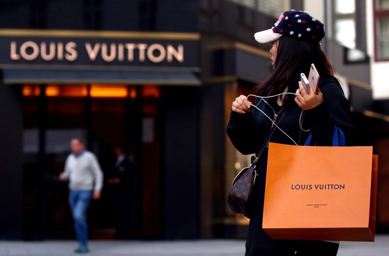 FILE PHOTO: Woman with a Louis Vuitton-branded shopping bag looks towards the entrance of a branch store by LVMH Moet Hennessy Louis Vuitton in Vienna