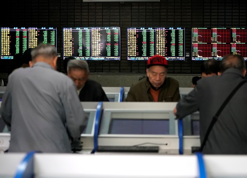 Investors look at computer screens showing stock information at a brokerage house in Shanghai