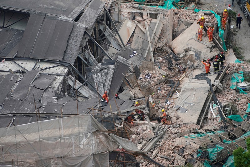 Firefighters work at the site where a building collapsed, in Shanghai