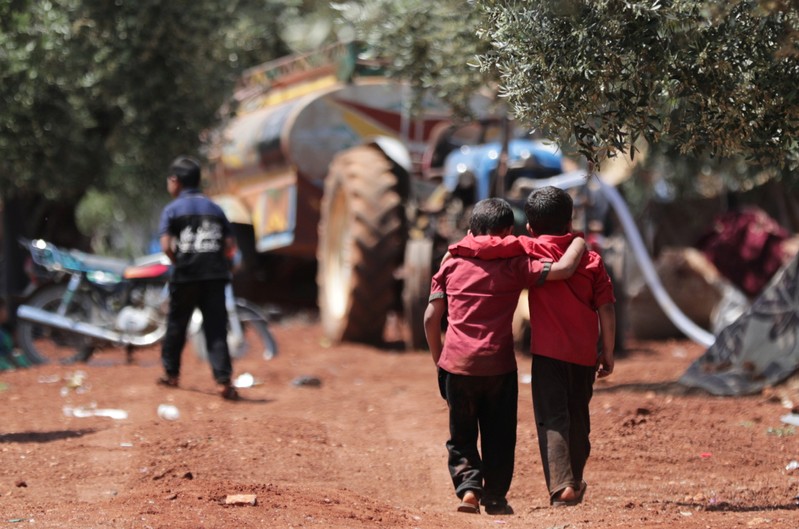 Displaced Syrian children walk together in an olive grove at Atmeh town, Idlib province