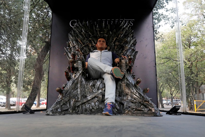 FILE PHOTO: A visitor poses for a photograph as he sits on a replica of the iron throne, as part of the promotion of the final season of