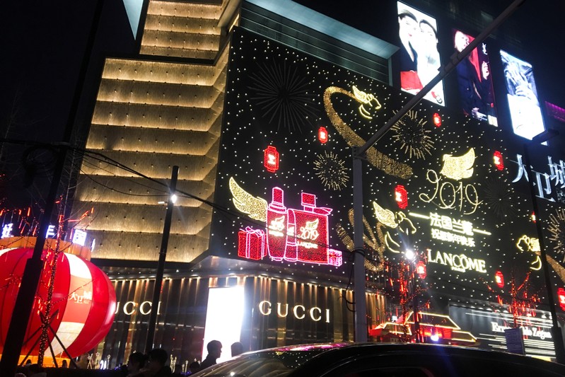 Neon signs in the shapes of luxury brand names illuminate the facade of David Plaza, a shopping mall in Zhengzhou