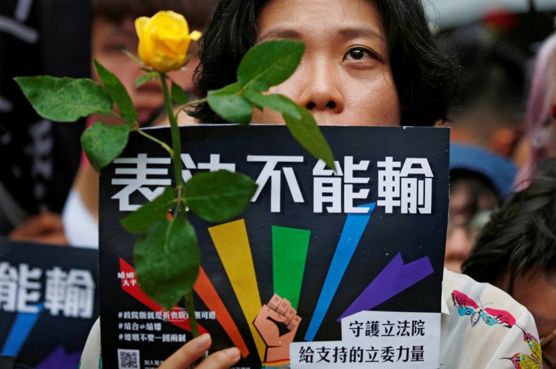 A same-sex marriage supporter holds rose to mourn those who committed suicide due to discrimination during a parliament vote on three draft bills of a same-sex marriage law, outside the Legislative Yuan in Taipei