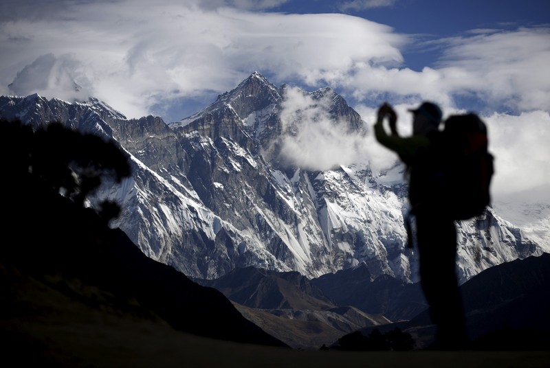 FILE PHOTO: A tourist is silhouetted as he takes pictures of Mount Nuptse as Mount Everest is covered with clouds in Solukhumbu district, also known as the Everest region