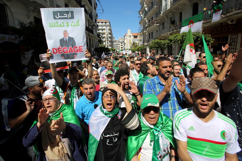 FILE PHOTO: A demonstrator holds a banner depicting interim president Abdelkader Bensalah during a protest demanding the removal of Algeria's ruling elite in Algiers