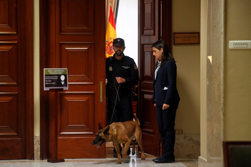 A police officer walks out with a dog from a room where four jailed Catalan politician will get their parliamentary credentials, in Madrid