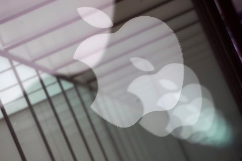 Apple company logos are reflected on the glass window outside an Apple store in Shanghai