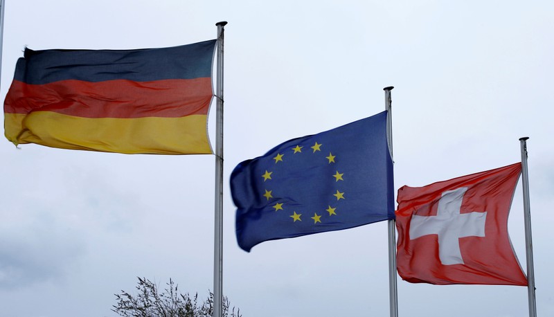 FILE PHOTO: An EU flag flies between Swiss and German national flags near the German-Swiss border in Rheinfelden, Germany