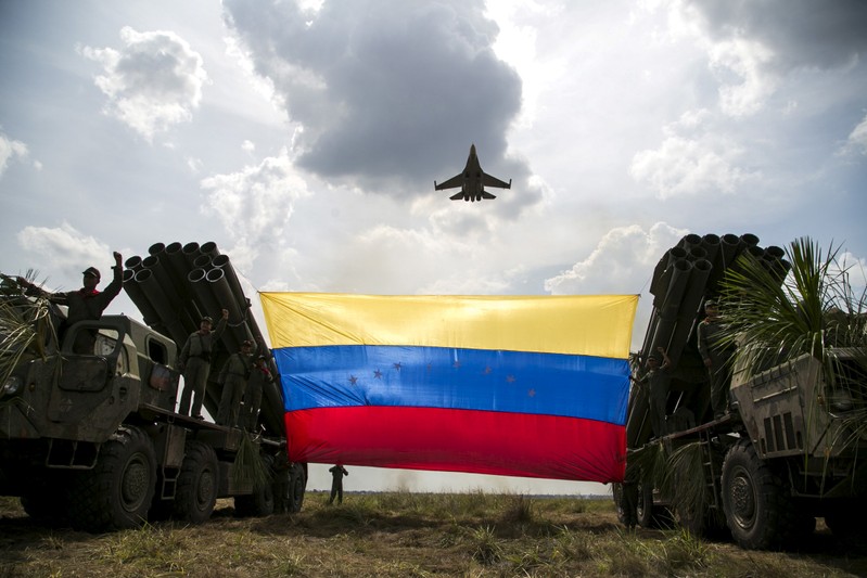 FILE PHOTO: A Russian-made Sukhoi Su-30MKV fighter jet of the Venezuelan Air Force flies over a Venezuelan flag tied to missile launchers, during the