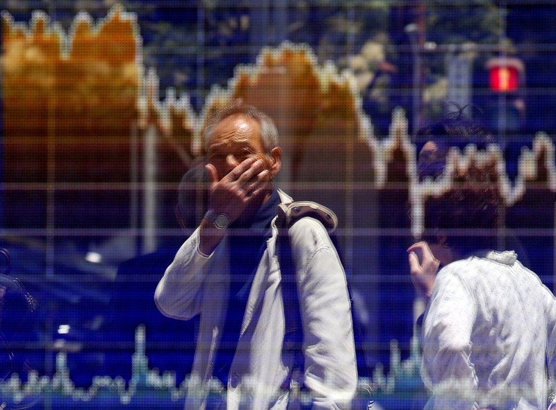 FILE PHOTO: A man is reflected in an electronic board showing the graph of the recent fluctuations of the TOPIX outside a brokerage in Tokyo