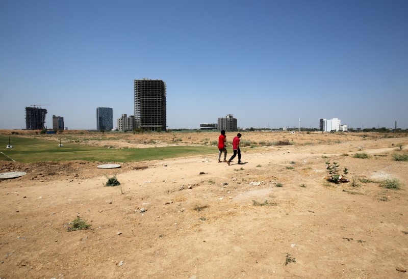 People walk past buildings under construction at the GIFT City at Gandhinagar