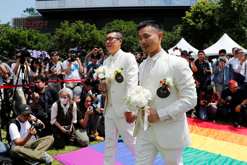 Gay newlyweds walk on a giant rainbow flag at a pro same-sex marriage party after registering their marriage in Taipei