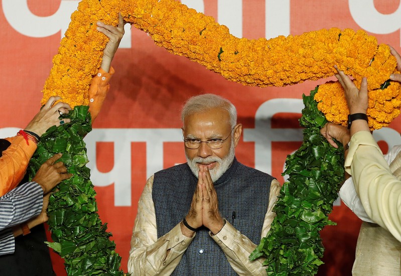 Indian Prime Minister Narendra Modi gestures as he is presented with a garland by Bharatiya Janata Party (BJP) leaders after the election results in New Delhi