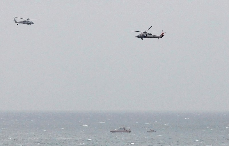 FILE PHOTO: FILE PHOTO: A Iranian Revolutionary Guard boat is seen near the U.S. aircraft carrier USS George H. W. Bush in the Strait of Hormuz as U.S. Navy helicopters hover nearby