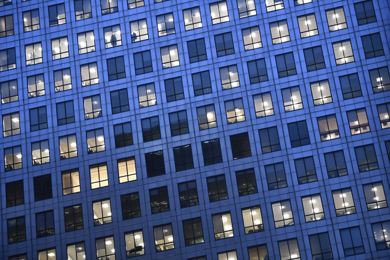 Office lights are on at dusk in the Canary Wharf financial district, London