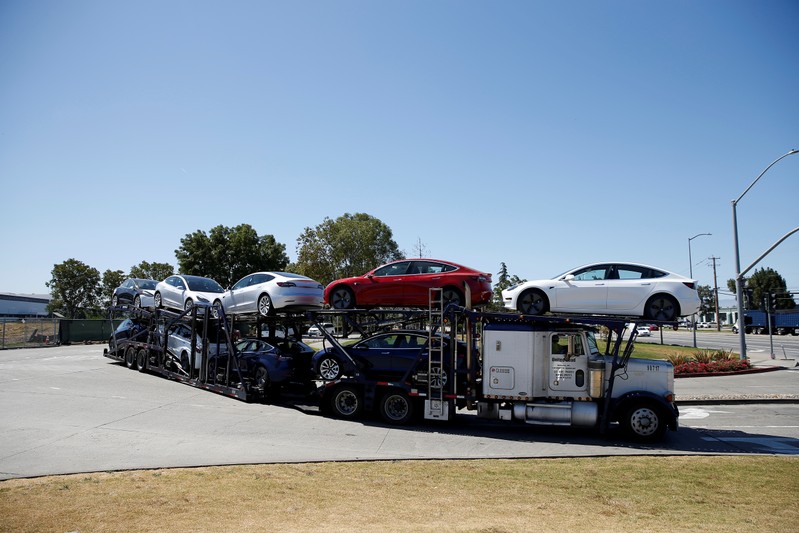 FILE PHOTO: A car carrier trailer carries Tesla Model 3 electric sedans, is seen outside the Tesla factory in Fremont