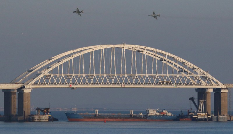 Russian jet fighters fly over a bridge connecting the Russian mainland with the Crimean Peninsula with a cargo ship beneath it after three Ukrainian navy vessels were stopped by Russia from entering the Sea of Azov via the Kerch Strait in the Black Sea
