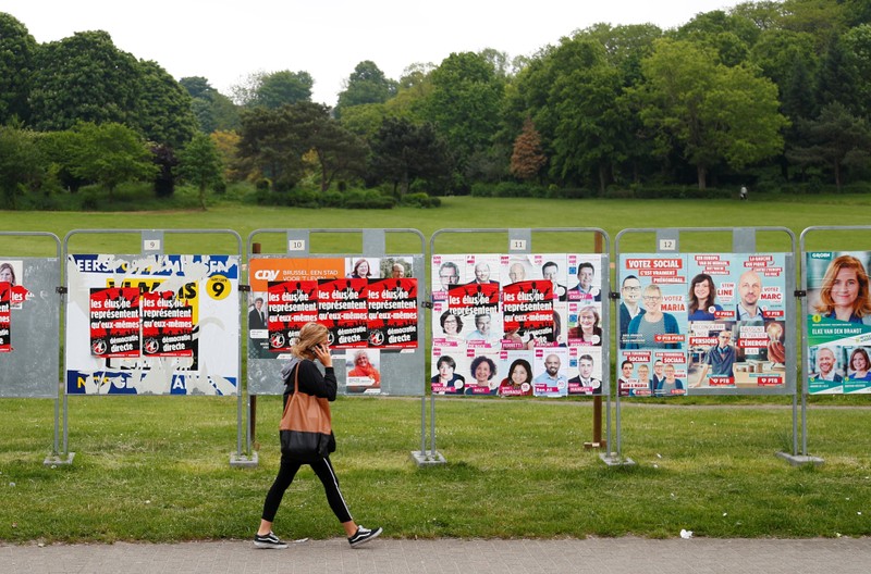 A woman walks past election campaign billboards in Brussels