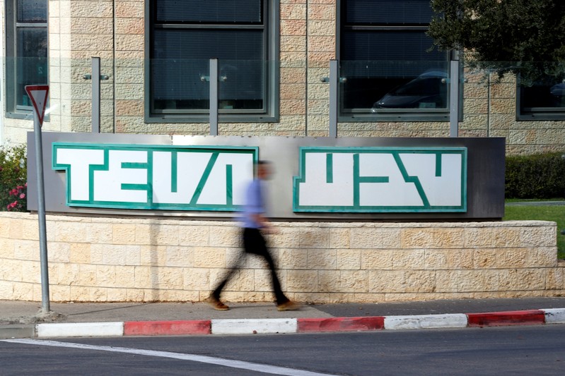 A man walks past the logo of Teva Pharmaceutical Industries at their plant in Jerusalem