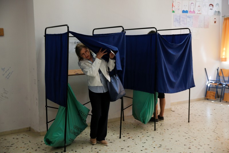 A woman exits the polling booth before casting her vote for the European and local elections at a polling station in Athens