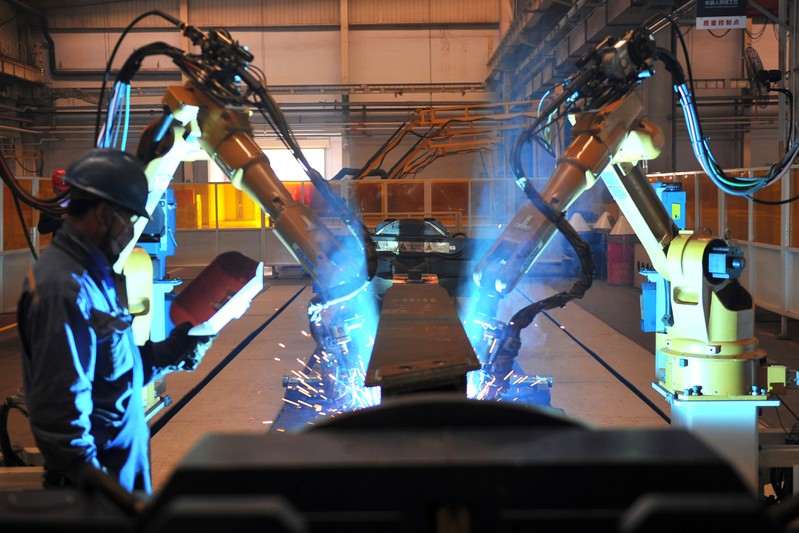 FILE PHOTO: Worker stands next to robotic arms welding pump truck part at a factory of the Foton Loxa Heavy Machinery Co in Zhangjiakou, Hebei