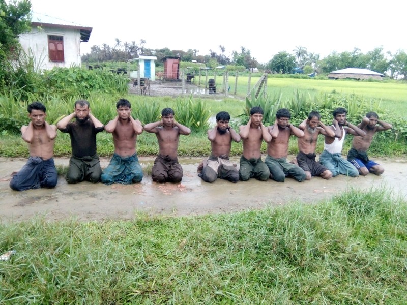 Ten Rohingya Muslim men with their hands bound kneel in Inn Din village