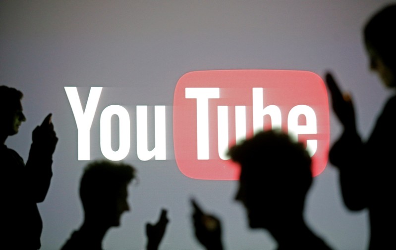 FILE PHOTO: People pose with mobile devices in front of projection of Youtube logo in this picture illustration taken in Zenica