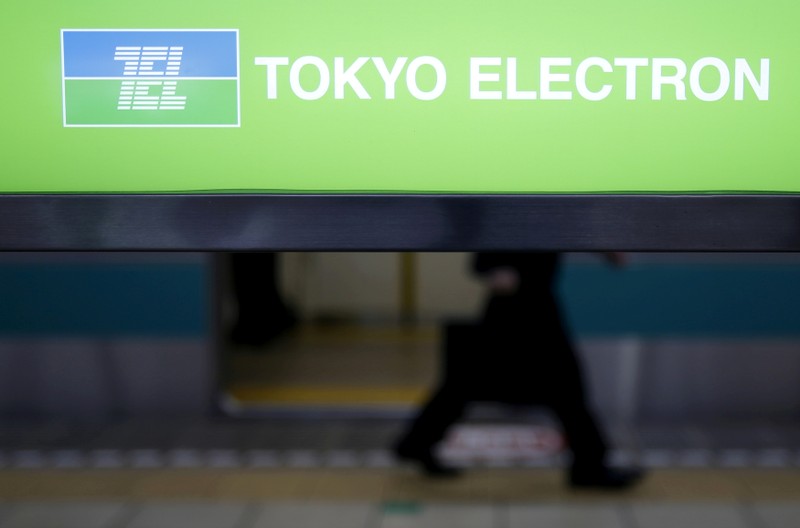 FILE PHOTO: A man walks behind a signboard with logo of Tokyo Electron Ltd in Tokyo