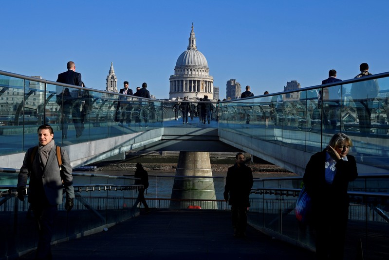 FILE PHOTO: Workers are seen crossing the Millennium Bridge, with St Paul's Cathedral seen behind during the morning rush hour in London