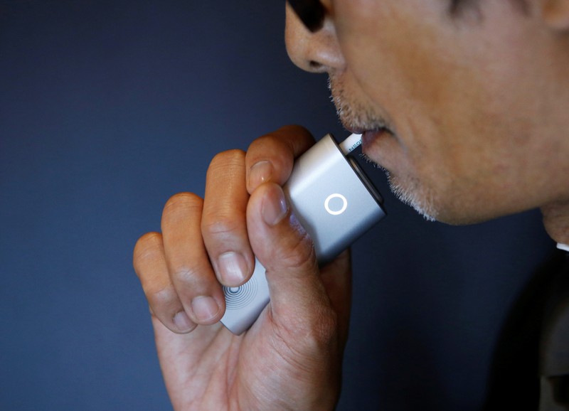 A staff of British American Tobacco Japan demonstrates its new tobacco heating system device 'glo' after a news conference in Tokyo