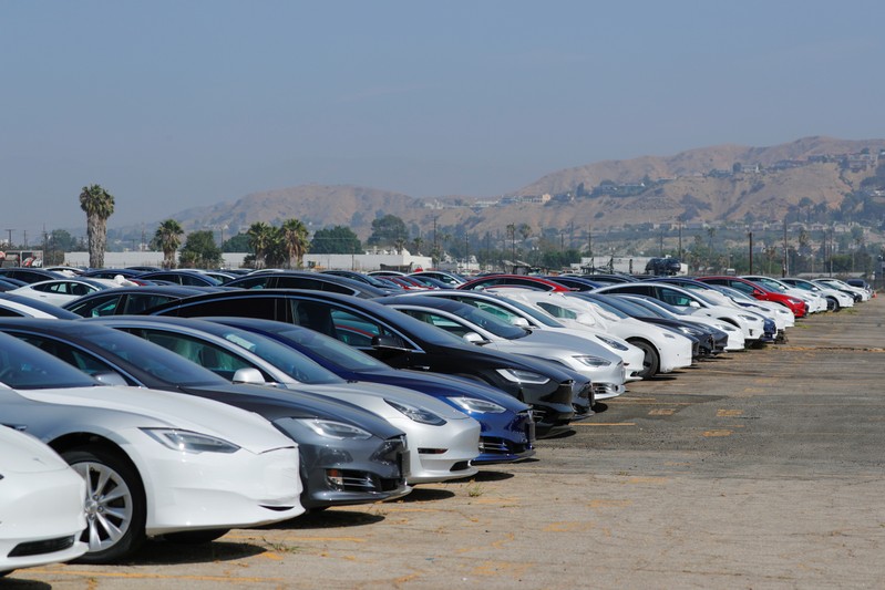 Newly manufactured Tesla vehicles are shown parked in a large lot next to the airport in Burbank, California