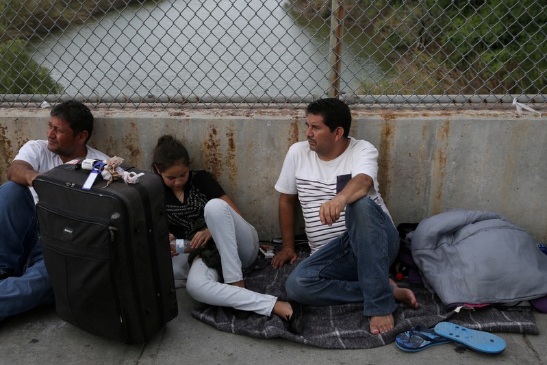 FILE PHOTO: Asylum seekers wait on the Mexican side of the Brownsville-Matamoros International Bridge after being denied entry by U.S. Customs and Border Protection officers near Brownsville