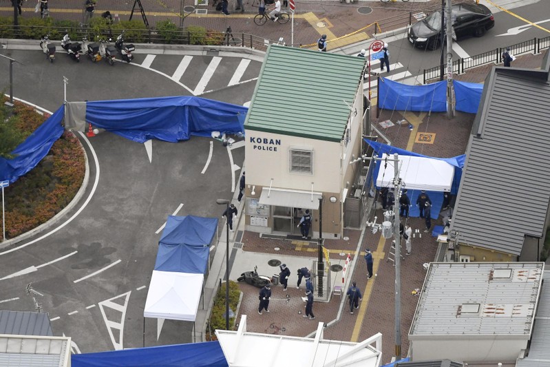 An aerial view shows police officers investigating the site where a police officer was found stabbed in front of a police box and the officer's gun, loaded with several bullets, was stolen, in Suita, Osaka
