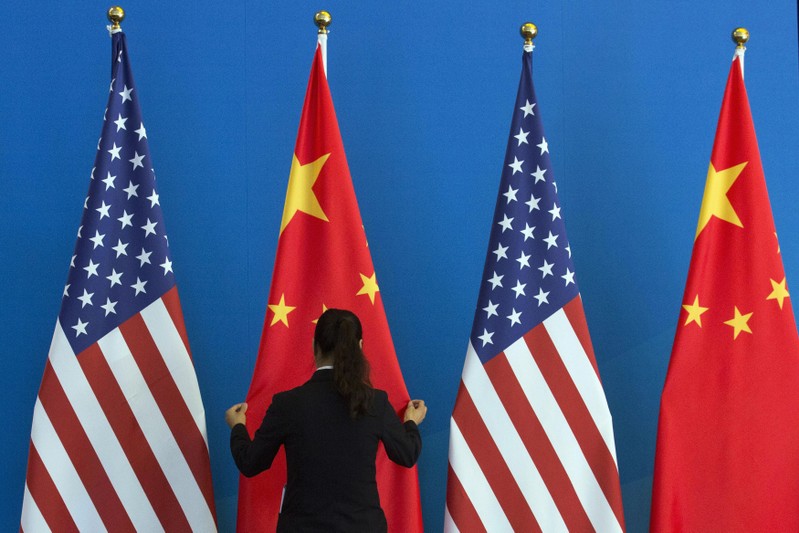 FILE PHOTO: A Chinese woman adjusts a Chinese national flag next to U.S. national flags before a Strategic Dialogue expanded meeting, part of the U.S.-China Strategic and Economic Dialogue (S&ED) in Beijing