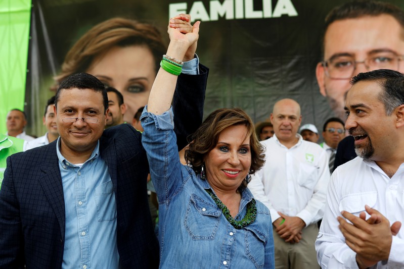 Sandra Torres, presidential candidate for the National Unity of Hope (UNE), raises her arms flanked by members of her party during her closing campaign rally in Villanueva