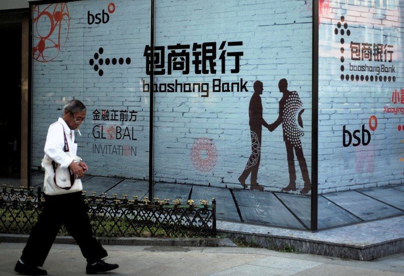 FILE PHOTO: Man walks past a building with an advertisement of Baoshang Bank in Beijing