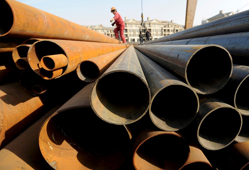FILE PHOTO: A labourer walks on steel pipes at a steel market in Hefei