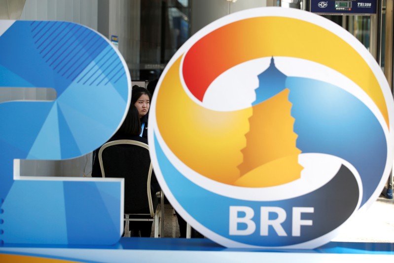 FILE PHOTO: A member of the security personnel sits behind a logo of the Belt and Road Forum at the China National Convention Center
