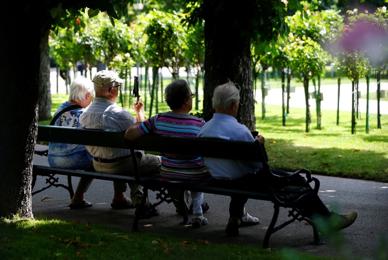 FILE PHOTO: A group of elderly people sit in the shade in a park in Vienna