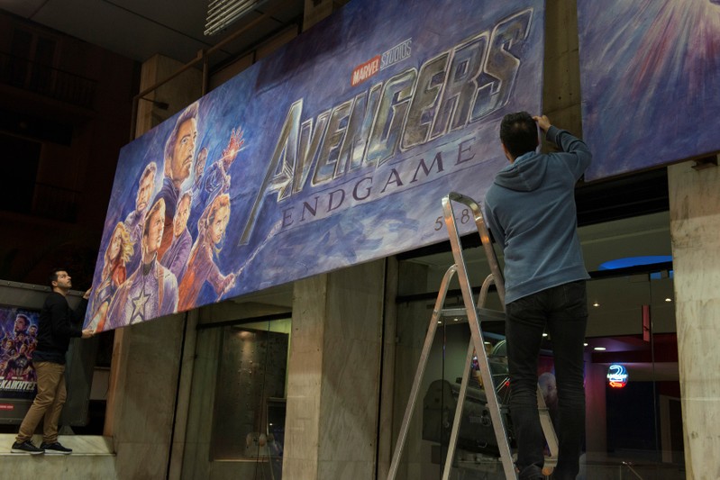 Two men place a painted billboard of the