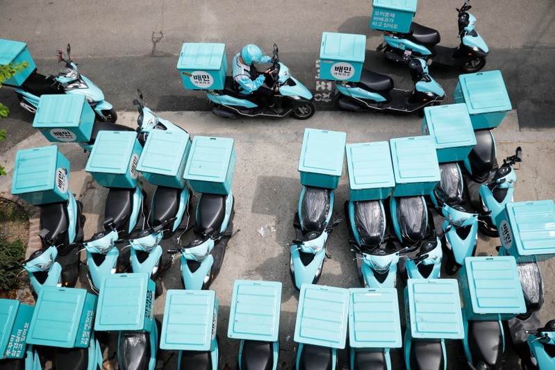An employee of Baemin Rider checks his mobile phone before delivery in Seoul