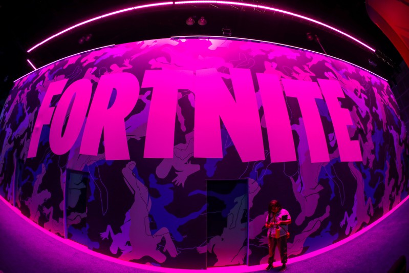 An attendee stops to text next to Epic Games Fortnite sign at E3, the annual video games expo revealing the latest in gaming software and hardware in Los Angeles