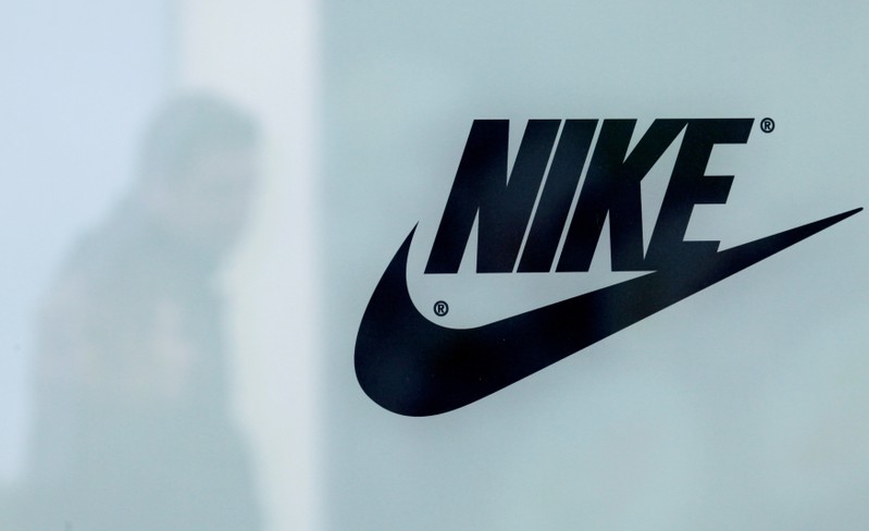FILE PHOTO: A customer is reflected in a shop window decorated with Nike store logo at the outlet village Belaya Dacha outside Moscow