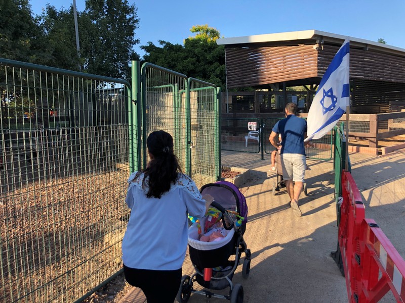 Visitors walk past an Israeli flag at a park in the northern Israeli town of Afula
