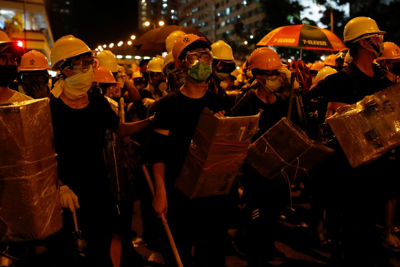 Anti-extradition bill protesters hold shields made from cardboard as they face riot police after a march at Sha Tin District of East New Territories, Hong Kong