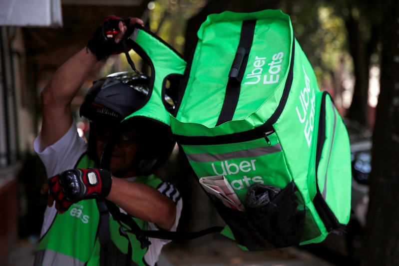 FILE PHOTO: A man puts on a delivery bag with the logo of Uber Eats in Mexico City
