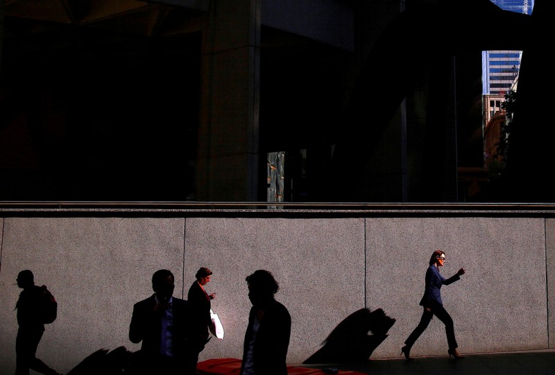 A woman carries a shopping bag as she walks with other pedestrians along a street on a spring day in the central business district of Sydney