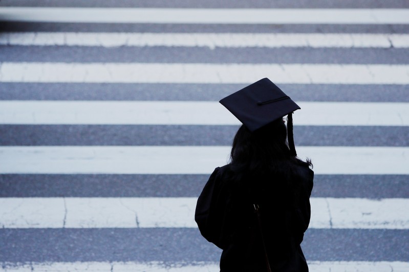 FILE PHOTO: A graduating student waits to cross the street before Commencement Exercises at MIT in Cambridge